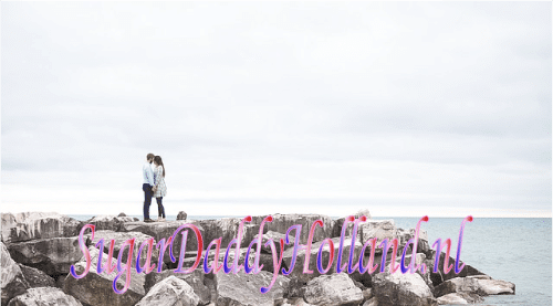 Man en vrouw omhelzen elkaar van verre met de zee op de achtergrond